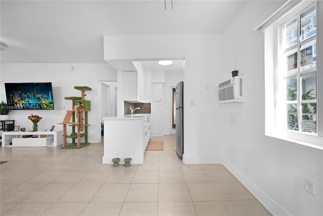 kitchen with stainless steel refrigerator, white cabinets, a healthy amount of sunlight, and light tile patterned floors