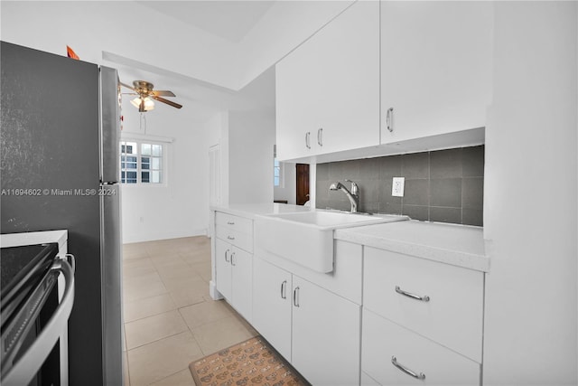 kitchen featuring decorative backsplash, light tile patterned flooring, ceiling fan, white cabinets, and stainless steel electric range