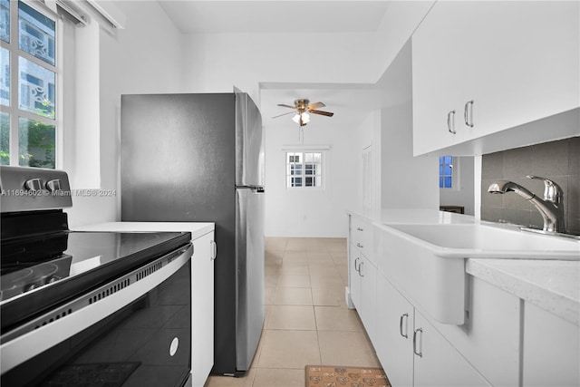 kitchen featuring sink, decorative backsplash, light tile patterned floors, white cabinetry, and stainless steel appliances