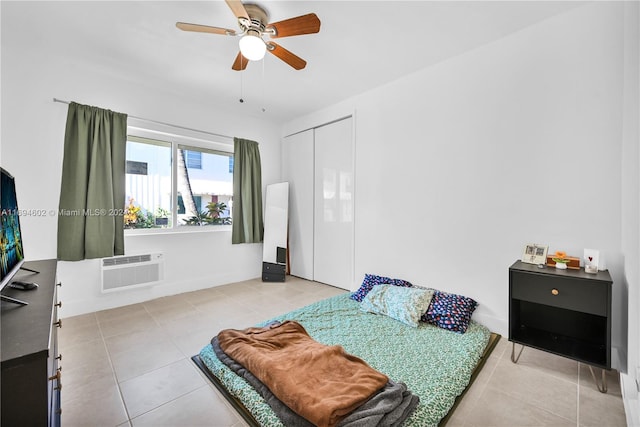 bedroom with an AC wall unit, ceiling fan, a closet, and light tile patterned floors