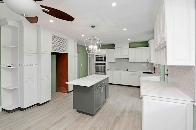 kitchen with white cabinets, a center island, light stone countertops, and stainless steel appliances