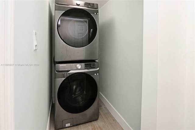 clothes washing area with light wood-type flooring and stacked washing maching and dryer