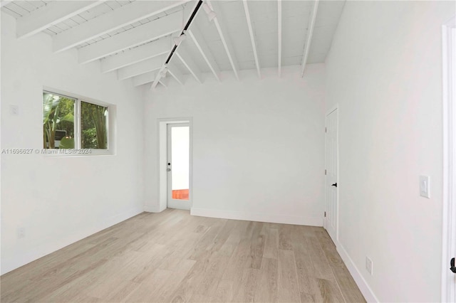 spare room with light hardwood / wood-style flooring and lofted ceiling with beams