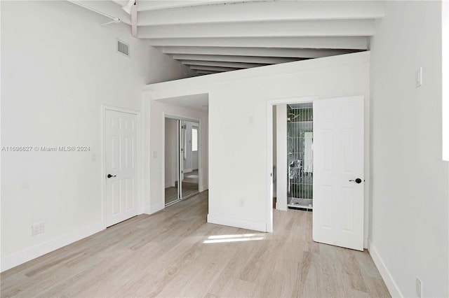 spare room with lofted ceiling with beams and light hardwood / wood-style floors