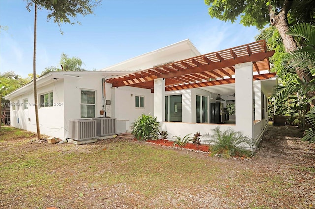 rear view of house featuring a pergola, a yard, and central AC