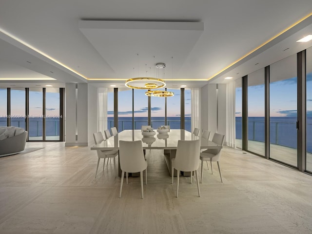 dining space featuring a chandelier, a water view, and a wall of windows