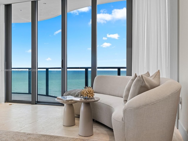 living room with a wall of windows, a water view, and plenty of natural light