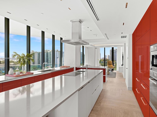 kitchen with island exhaust hood, black electric stovetop, light parquet floors, sink, and oven