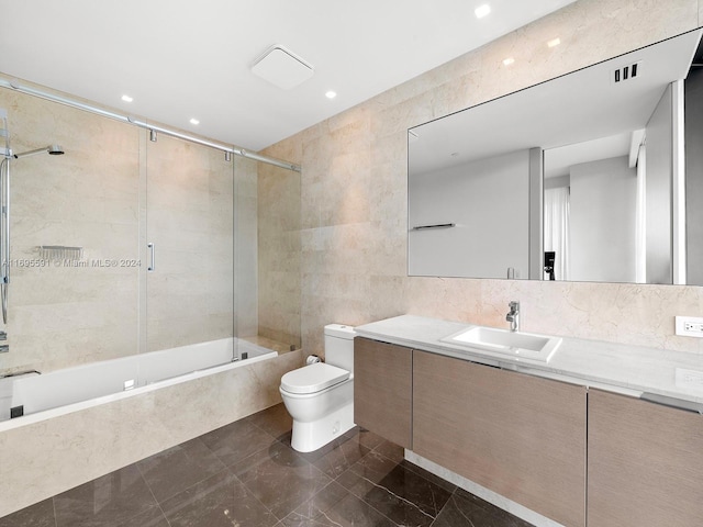 full bathroom featuring vanity, toilet, tile walls, and enclosed tub / shower combo