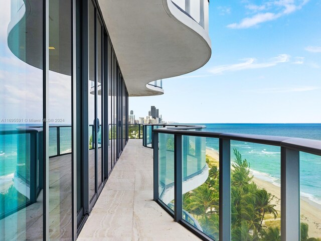 balcony with a water view and a view of the beach