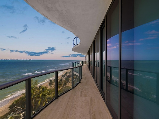 balcony at dusk with a beach view and a water view