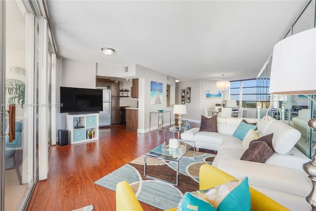 living area featuring floor to ceiling windows, a textured ceiling, baseboards, and wood finished floors