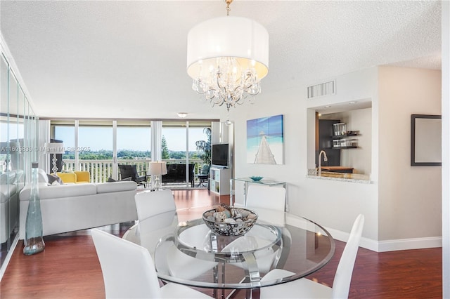 dining area with wood finished floors, baseboards, visible vents, a textured ceiling, and a notable chandelier