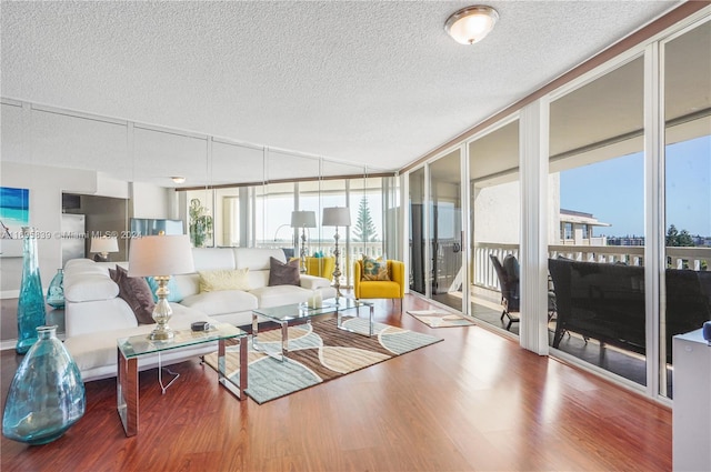 living room featuring hardwood / wood-style floors, plenty of natural light, expansive windows, and a textured ceiling