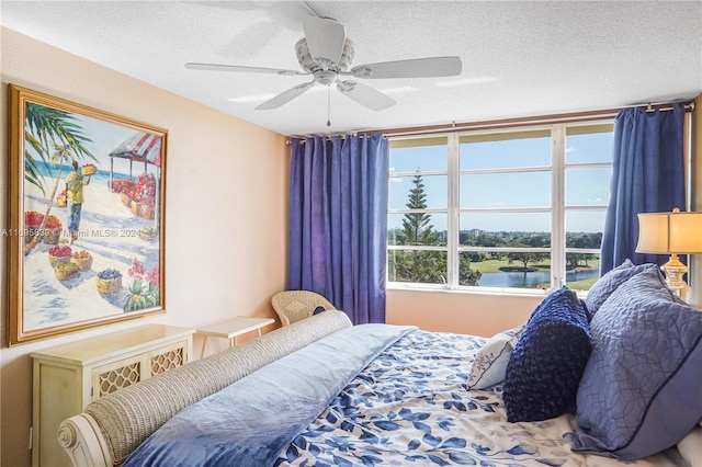 bedroom featuring a textured ceiling, a water view, and ceiling fan