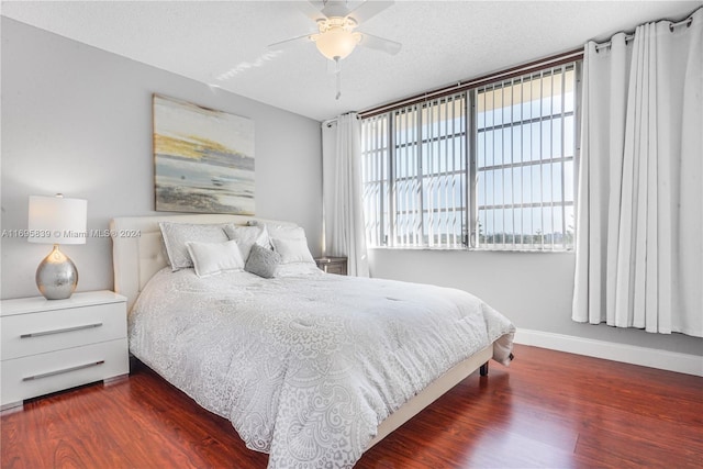 bedroom with ceiling fan, dark hardwood / wood-style flooring, and a textured ceiling