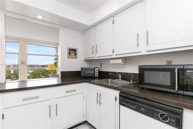 kitchen featuring white dishwasher, white cabinets, sink, and a textured ceiling