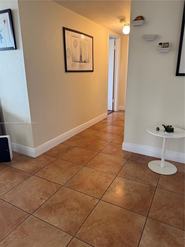 hall featuring tile patterned floors and a textured ceiling