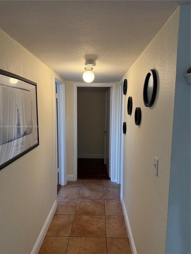 corridor with tile patterned flooring and a textured ceiling