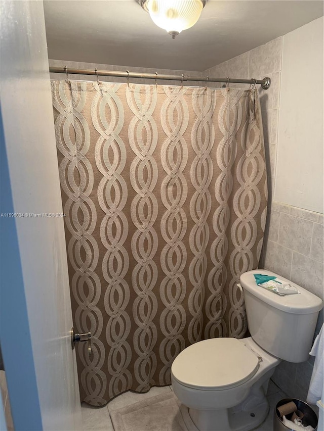 bathroom featuring toilet and tile walls