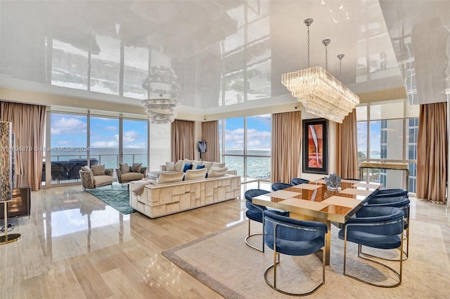 dining room with a water view, light wood-type flooring, a high ceiling, and an inviting chandelier