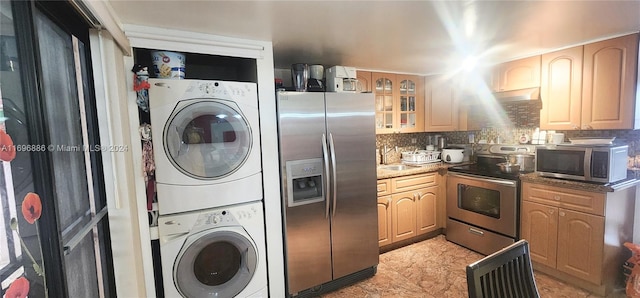 kitchen with light stone countertops, appliances with stainless steel finishes, tasteful backsplash, sink, and stacked washer and dryer