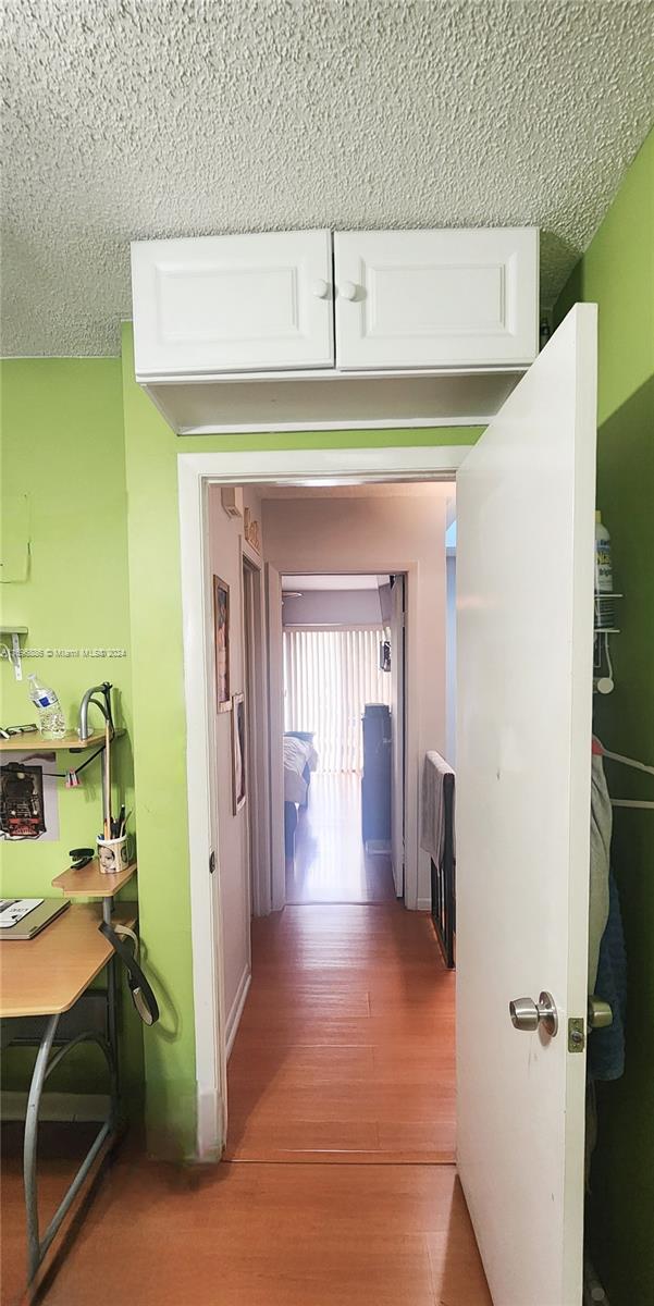 hallway featuring a textured ceiling and hardwood / wood-style flooring