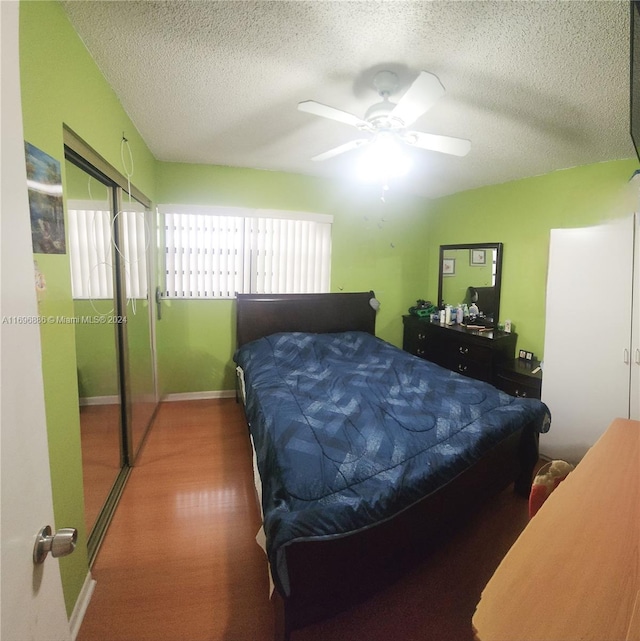 bedroom with a textured ceiling, hardwood / wood-style flooring, and ceiling fan