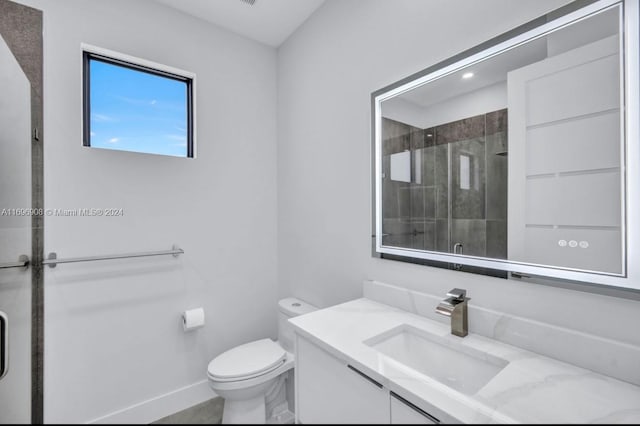 bathroom featuring vanity, toilet, and a shower with door