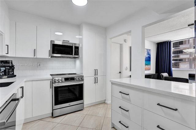 kitchen with decorative backsplash, white cabinetry, light tile patterned floors, and stainless steel appliances