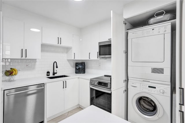 kitchen with white cabinets, stacked washer / drying machine, sink, and stainless steel appliances