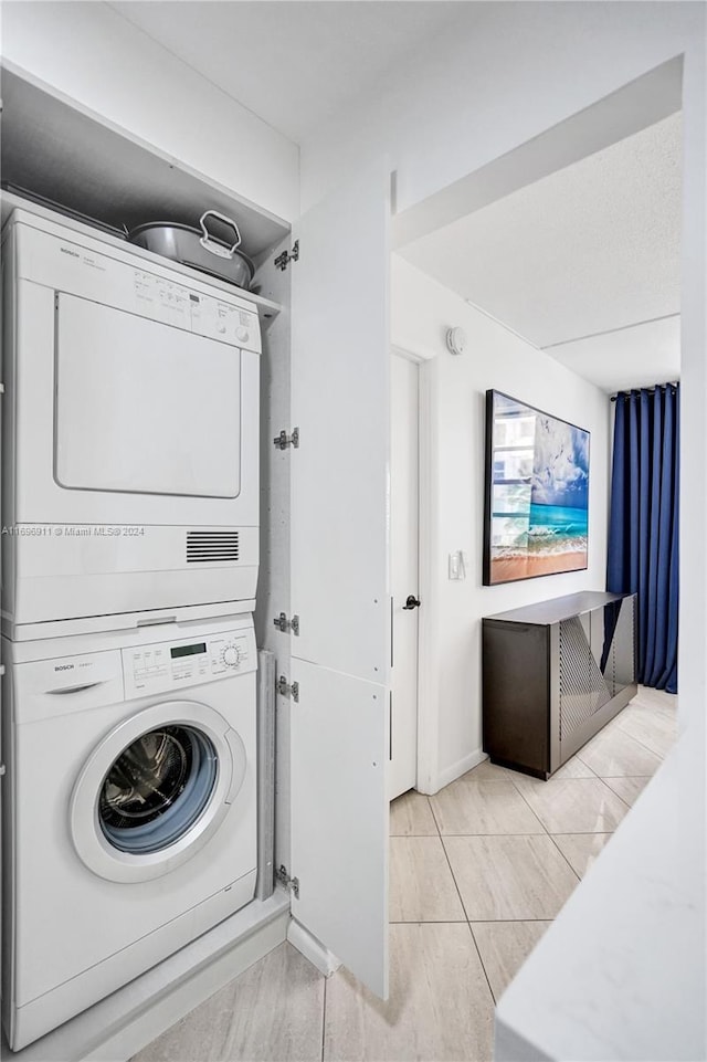 laundry area featuring stacked washer / dryer and light tile patterned floors