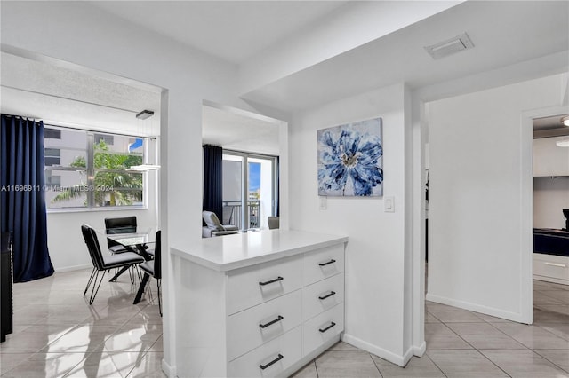 interior space with kitchen peninsula, light tile patterned floors, white cabinetry, and a wealth of natural light