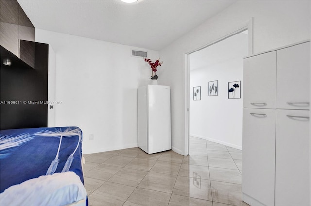 bedroom featuring white refrigerator, a closet, and light tile patterned flooring