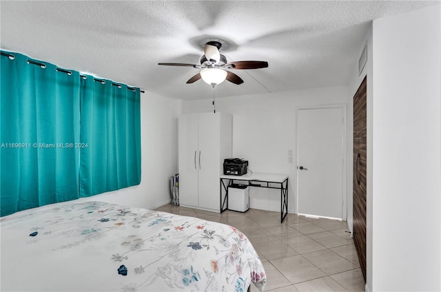 tiled bedroom with ceiling fan and a textured ceiling