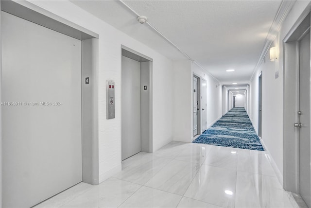 hall featuring elevator, a textured ceiling, and ornamental molding