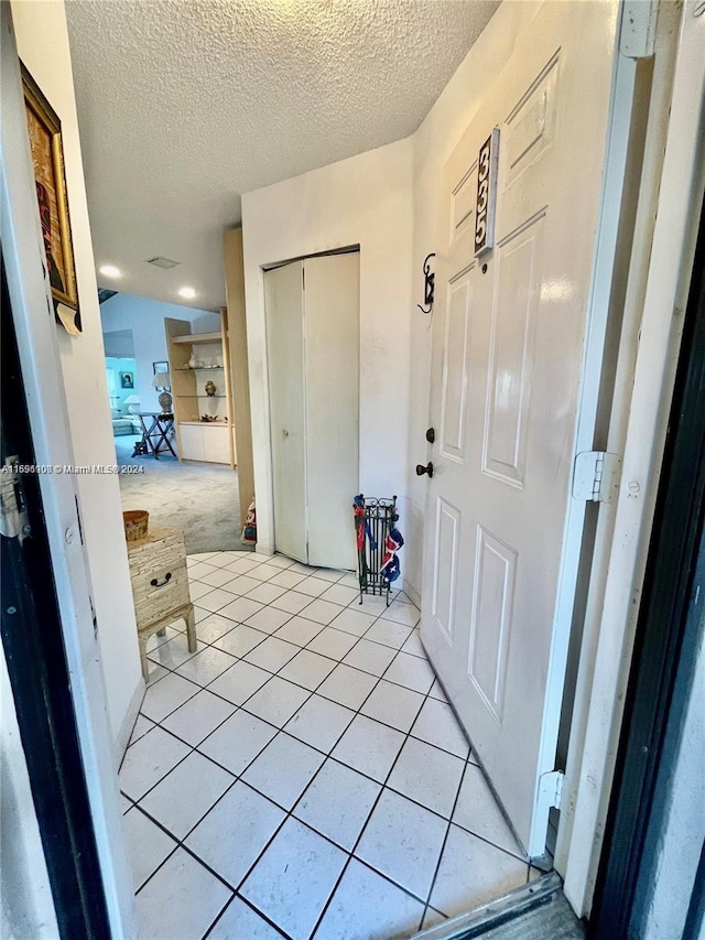 corridor featuring light tile patterned floors and a textured ceiling