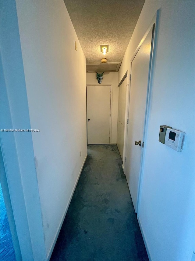 hall featuring carpet and a textured ceiling