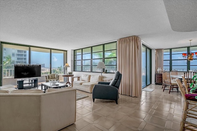 living room with a water view, expansive windows, a chandelier, and a textured ceiling