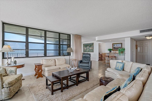 tiled living room featuring a water view and a textured ceiling