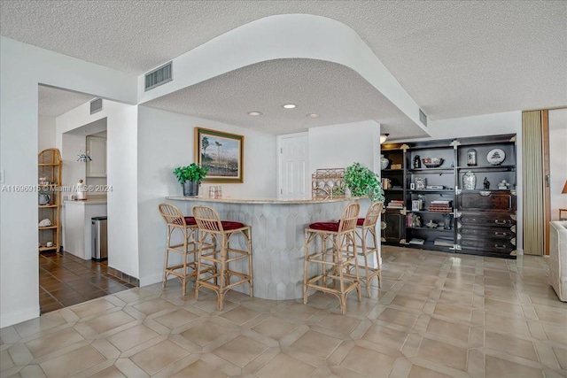 kitchen featuring a breakfast bar, kitchen peninsula, and a textured ceiling