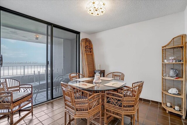 tiled dining room featuring a textured ceiling and floor to ceiling windows