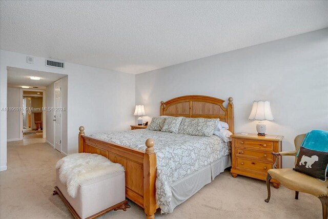 bedroom featuring light colored carpet and a textured ceiling