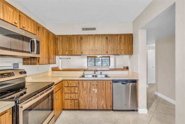 kitchen featuring light tile patterned floors, sink, appliances with stainless steel finishes, and tasteful backsplash