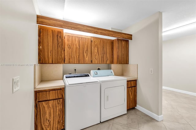 clothes washing area featuring separate washer and dryer, light tile patterned floors, cabinets, and a textured ceiling