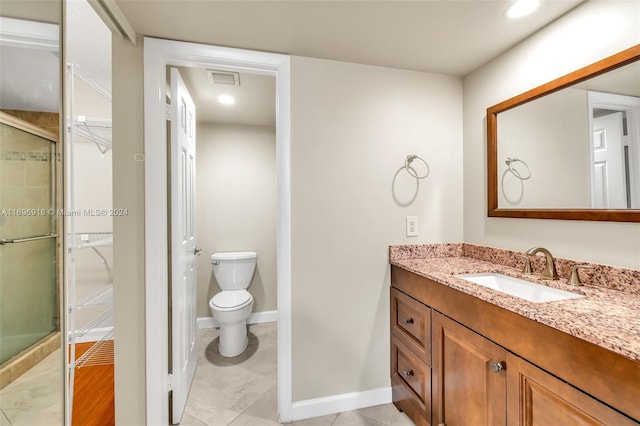 bathroom with tile patterned floors, vanity, an enclosed shower, and toilet