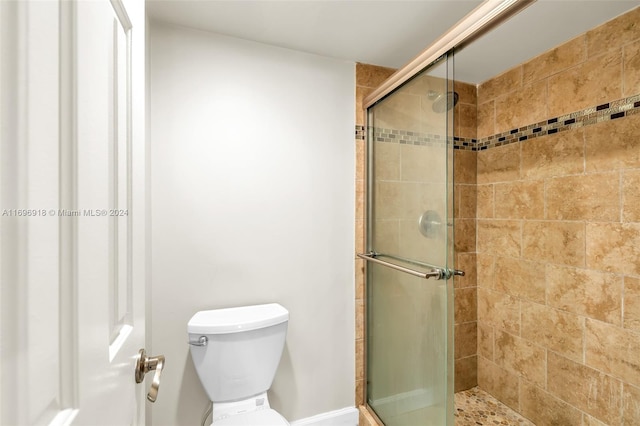 bathroom featuring a shower with door and toilet