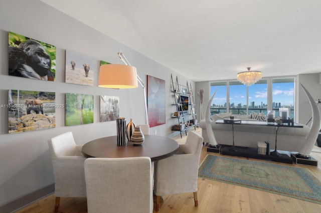 dining room with hardwood / wood-style floors, a wall of windows, and an inviting chandelier