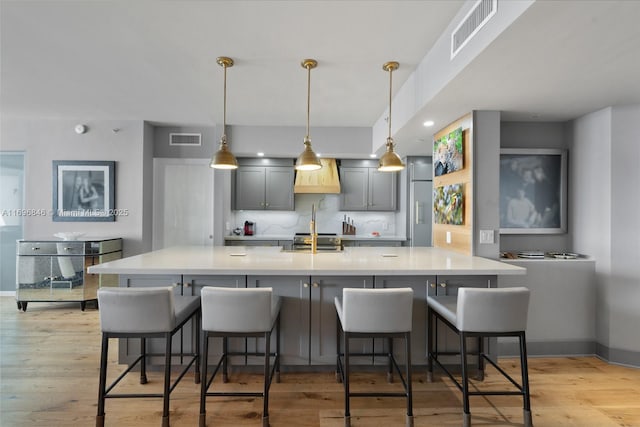 kitchen with a kitchen breakfast bar, tasteful backsplash, decorative light fixtures, light hardwood / wood-style flooring, and stainless steel range oven