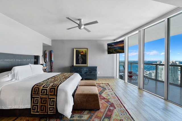 bedroom with access to exterior, wood-type flooring, floor to ceiling windows, and ceiling fan